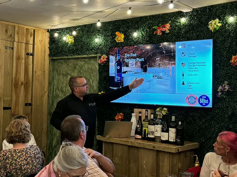 Jamie pointing to the wine on the screen as guests follow along